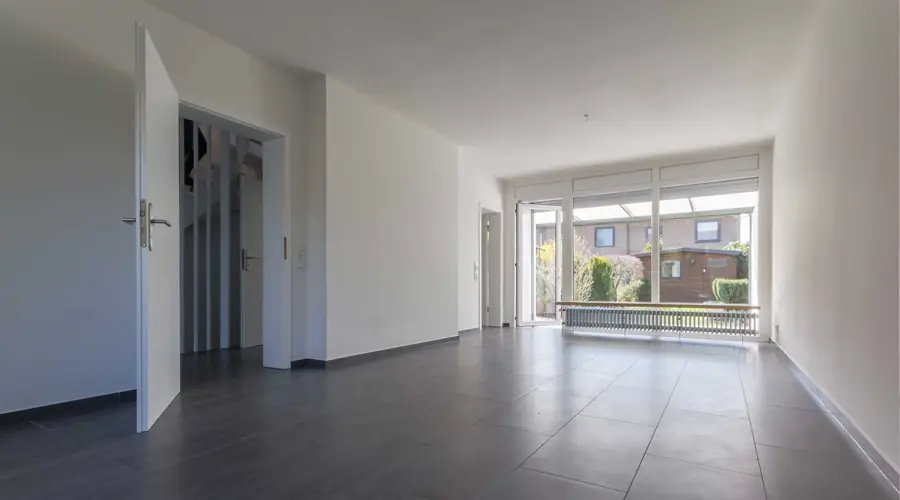 Wohnraum mit dunklem Boden und Fensterfront zum Garten